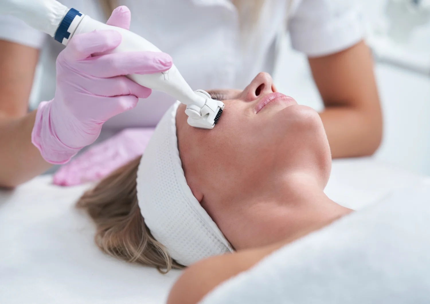 Kobieta podczas zabiegu oczyszczania wodorowego twarzy w gabinecie kosmetycznym.